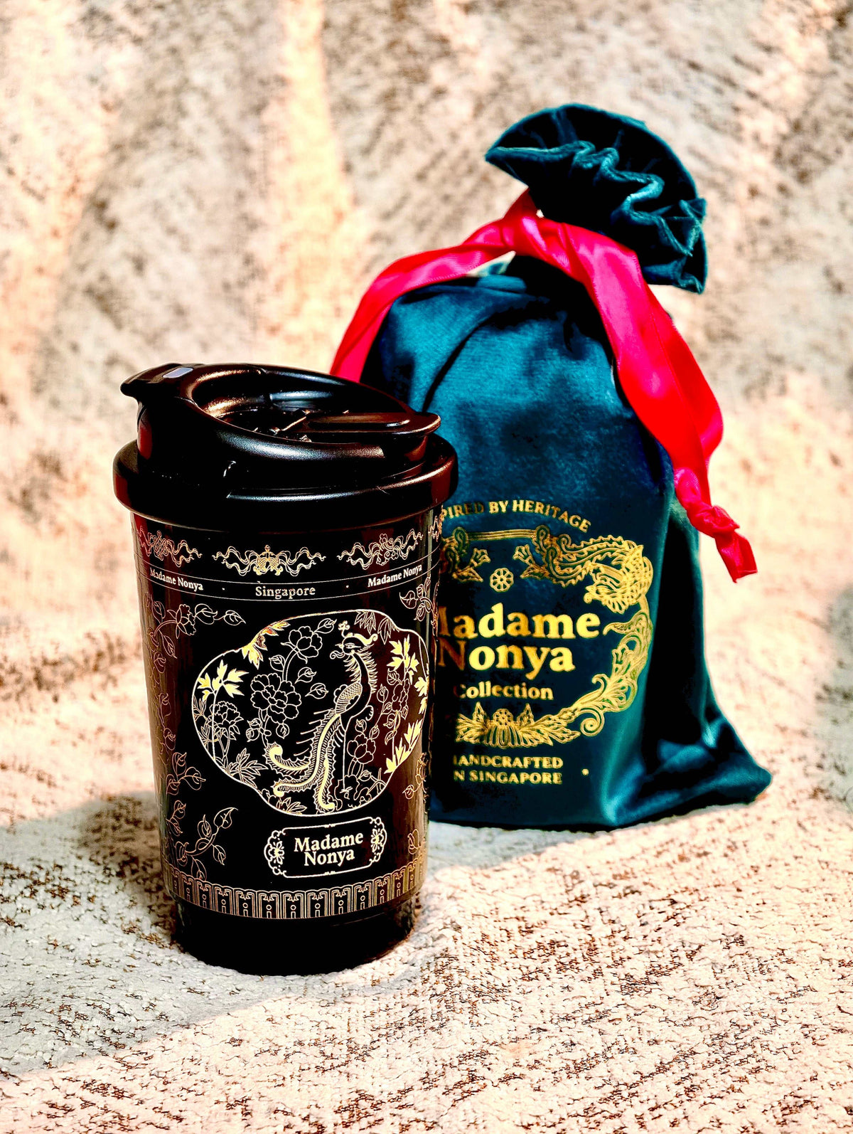 Gilded Heritage Coffee Tumbler black stainless steel with gold phoenix and peony motif, shown with teal and red decorative pouch